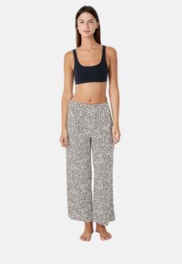 Top corto nero e pantaloni da pigiama bianchi con un motivo a stampa leopardata. Vestibilità ampia e tessuto traspirante con gambe larghe.
