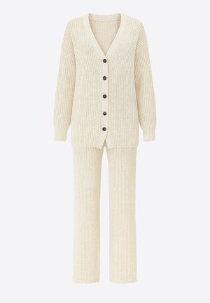 Kremowy sweter na guziki z dekoltem w serek i teksturowanym wzorem, zestawiony z pasującymi prążkowanymi spodniami dzianinowymi.