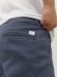 Sötétkék farmernadrág sima textúrával, hátsó zsebbel és egy kis fehér címkével, amelyen a "JACK & JONES" márkajelzés található.