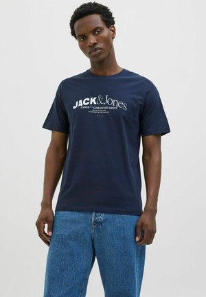 Navy blue cotton t-shirt with short sleeves featuring a white logo print "JACK & Jones Core Creative Dept." on the front.