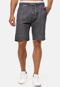 Grå, teksturerede shorts med snor i livet, opfoldede kanter og sidelommer, parret med hvide sneakers.