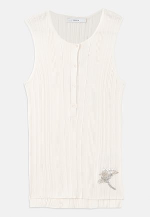 Hihaton, ribbed top off-white kankaasta, jossa on napitettu etuosa ja metallinen kukkakirjont yksityiskohta helmassa.