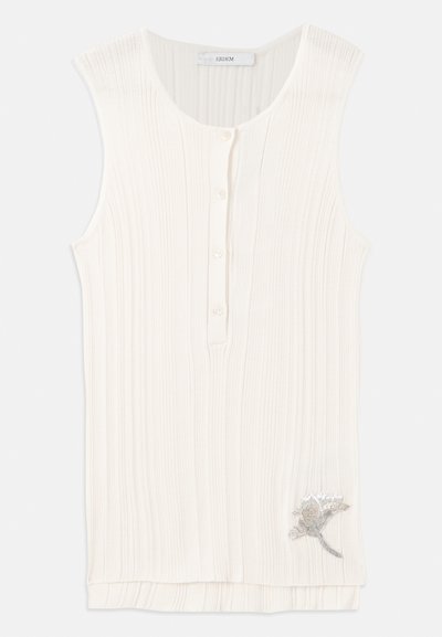 Hihaton, ribbed top off-white kankaasta, jossa on napitettu etuosa ja metallinen kukkakirjont yksityiskohta helmassa.