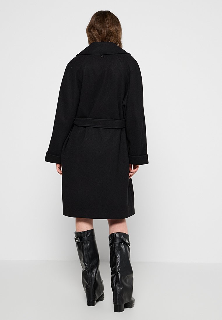 Czarny płaszcz o długości do kolan z paskiem w talii, szerokimi klapami i luźnym krojem. Wykonany z gładkiego materiału, z mankietami.