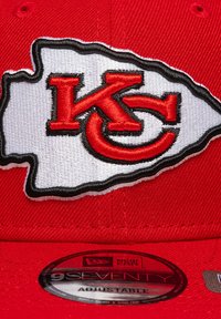 Rød justerbar kasket med et broderet Kansas City Chiefs-logo i sort og hvidt. Inkluderer et cirkulært New Era-mærke på skyggen.