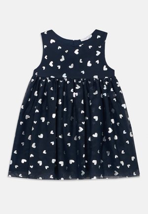 Mornarice plava haljina s pripijenom bezrukavom korzetom i raširenom suknjom, ukrašena sjajnim srebrnim uzorcima srca.