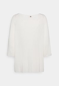 Maglione bianco lavorato a maglia con una consistenza morbida, scollatura ampia, maniche a tre quarti e un piccolo dettaglio con bottone sul retro.
