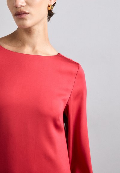 Rød satinbluse med rund halsudskæring og lange ærmer, der har en glat tekstur og minimale syninger.
