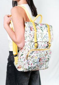 Floral patterned backpack with yellow straps and gold hardware. Rectangular shape with a zippered front pocket and adjustable straps.