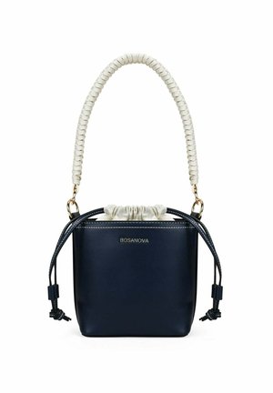 Bolso estilo cubo azul marino con asa trenzada blanca, cierre de cordón y herrajes dorados, con la marca BOSANOVA en el frontal.