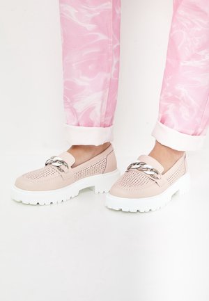 Lyserøde perforerede loafers med chunky hvide såler og sølvkædedetalje, båret med opsmøgede lyserøde og hvide mønstrede bukser.