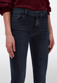 Tummaa farkkutakki, jossa on slim fit -malli, viisi taskua, vetoketjukiinnitys ja hienoiset haalistumat reiden lähellä.