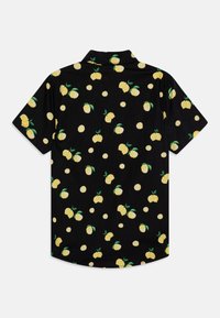 Chemise noire à manches courtes avec un motif de citrons jaunes et de tranches de citron dispersées sur le tissu.