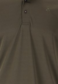 Oliivinvihreä polo-paita, joka on valmistettu sileästä kankaasta ja jossa on kahden napin suljenta sekä hienovarainen logo vaaleammassa sävyssä rinnassa.