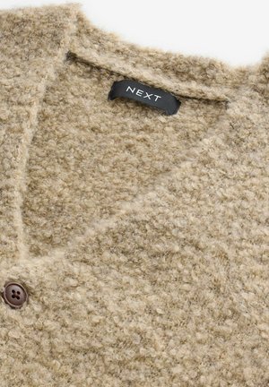 Beige Strickjacke aus einem strukturierten, flauschigen Stoff. Verfügt über einen V-Ausschnitt, einen braunen Knopfverschluss und ein schwarzes "NEXT"-Label im Inneren.