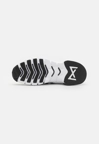 Sneaker sål, overvejende sort med hvide riller. Tekstureret mønster til traction, med et logo akcent i hælområdet.