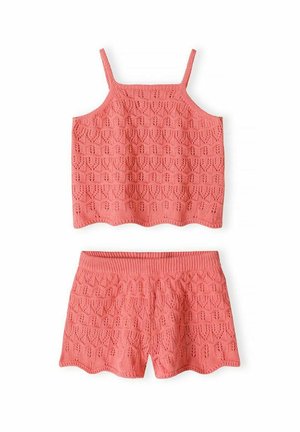 Koralowy różowy dziergany top na ramiączkach i pasujące do niego szorty z geometrycznym ażurowym wzorem i karbowanymi brzegami na białym tle.