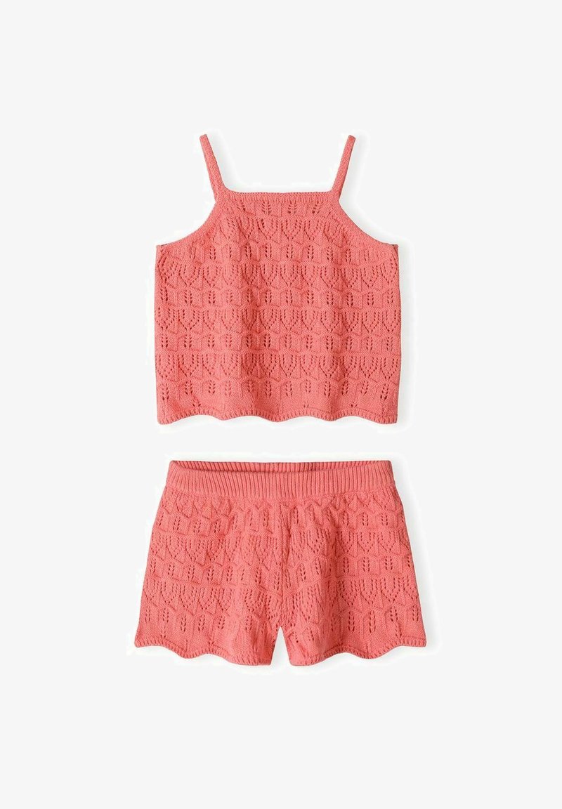 Ensemble débardeur en maille corail rose et short assorti avec un motif géométrique en ajouré et des bords festonnés sur fond blanc.