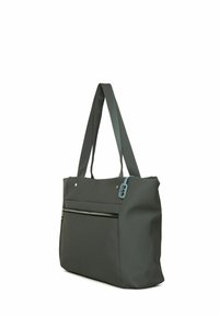 Sac fourre-tout gris fabriqué en tissu mat. Dispose de poignées doubles, d'une poche zippée à l'avant et d'une étiquette bleue avec du texte. Forme rectangulaire, texture lisse.