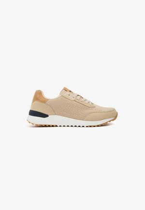 Zapatilla deportiva beige con una parte superior de malla texturizada, acentos sintéticos en tono marrón claro, entresuela blanca y suela de goma marrón; cuenta con cordones tradicionales.