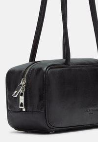 Czarna skórzana torebka w kształcie prostokąta, z mocnym zamkiem błyskawicznym, gładką teksturą i dwiema długimi rączkami. Widoczny minimalistyczny branding.