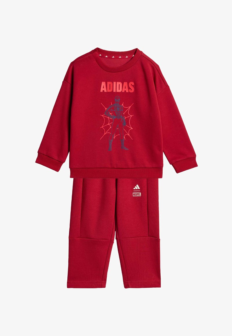 Crvena dukserica s "ADIDAS" logotipom i Spider-Man grafikom, uparen s odgovarajućim crvenim hlačama koje imaju "MARVEL" oznaku. Tkanina izgleda mekana.