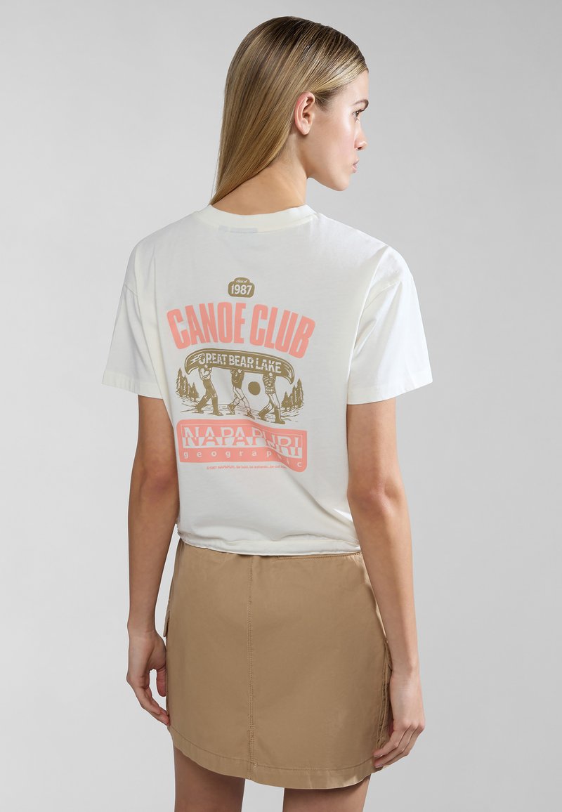 Witte katoenen t-shirt met een grafische print met de tekst "CANOE CLUB" en figuren, gecombineerd met een khaki rok. Korte mouwen, ontspannen fit.