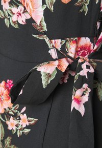 Tecido preto com um padrão floral apresentando flores rosas e vermelhas; inclui um detalhe de laço para um design ajustado; textura suave.