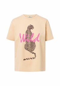 T-shirt en coton beige clair avec une silhouette de léopard marron et le mot "Wild" en rose. Manches courtes, col rond et coupe décontractée.