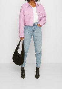 Lyhennetty vaaleanpunainen farkkutakki, jossa on kaksi etutaskua, valkoinen V-pääntie T-paita, vaaleansiniset farkut, musta teksturoitu käsilaukku ja mustat teräväkärkiset nilkkurit.