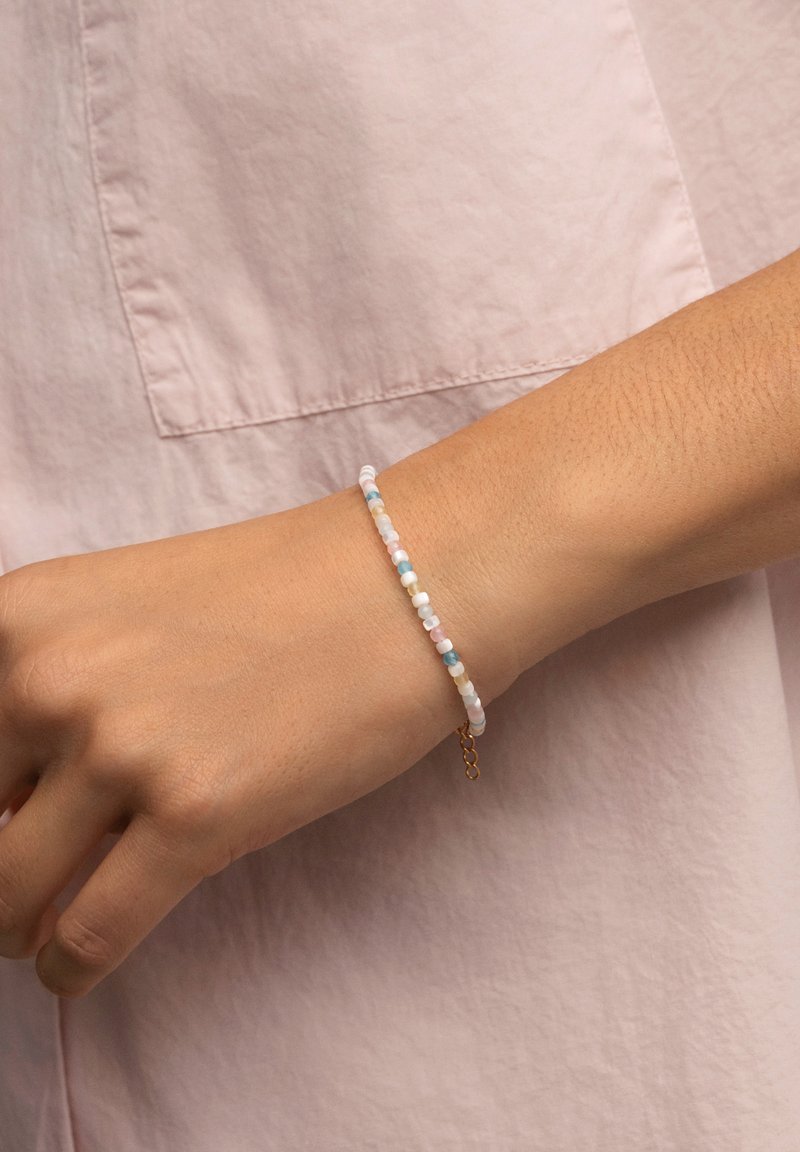 Bracciale di perline colorate con tonalità pastello di rosa, blu e bianco. Presenta un design sottile e delicato con una chiusura a catena dorata.