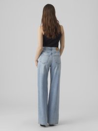 Ljust blå, högmidjade jeans med vid byxben och en subtilt urblekt textur. Har bakfickor och en brun läderetikett på midjebandet.