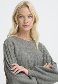 Maglione grigio lavorato a maglia con texture a coste, spalle scese e maniche lunghe e voluminose. Tessuto morbido di peso medio con scollatura rotonda.