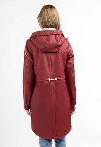 Giacca impermeabile rossa con cappuccio, caratterizzata da una vita affusolata, una texture liscia e un orlo posteriore più lungo. Accenti argento sulle maniche.