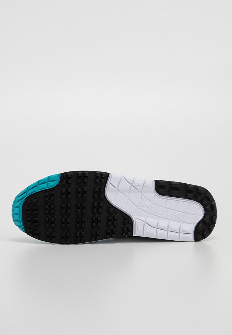 De schoenzool heeft een zwarte rubberen basis met een witte tussenzool en een turkooise accent. Geverfde oppervlakte met een gestructureerd profiel voor grip.