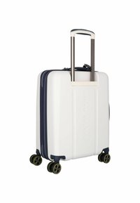 Maleta rígida blanca con acentos en azul marino, que cuenta con un mango retráctil, cuatro ruedas negras giratorias y estrías verticales en la superficie.