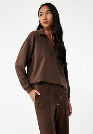 Bruine lange mouw pullover met een kraag en een V-halslijn, gecombineerd met bijpassende joggerbroeken met een trekkoord en zijzakken.