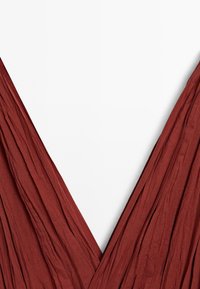 Maroon draped fabric with a deep V-neckline, showcasing its textured, flowing design against a plain white background.