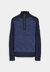 Le pull marine à demi-fermeture éclair présente un devant matelassé avec un motif en losanges, des manches en tricot, ainsi que des poignets et un ourlet côtelés pour un contraste de textures.