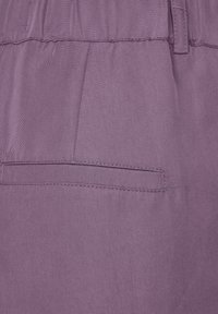 Lavendeltyg med en slät textur; har en sidoficka med en rak söm. Midjebandet är rynkat för en avslappnad passform.