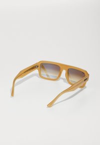 Ochelari de soare dreptunghiulari din plastic transparent galben. Lentile cu degradé și o ușoară nuanță. Brațe drepte, groase, cu detalii subtile de metal.