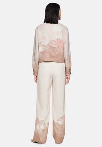 Floral sweatshirt in beige with light pink and white flowers; relaxed fit; long sleeves with cuff; paired with cream wide-leg trousers.