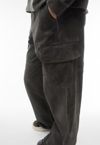 Pantaloni cargo neri con tasche laterali, dalla vestibilità facile, realizzati in tessuto strutturato. Presentano dettagli cuciti e un sottile logo.