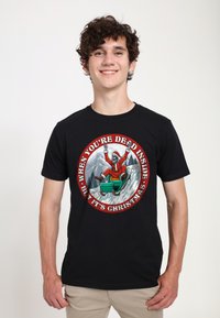 Camiseta de algodón negra con un gráfico circular que muestra a un Santa esqueleto en un trineo verde sobre un fondo nevado, con texto rojo.