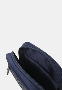 Borsa di stoffa blu navy con chiusura con zip e interno foderato. Presenta più scomparti interni per l'organizzazione. Texture liscia.