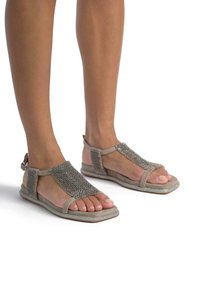 Beige Sandalen mit strukturiertem Obermaterial und silbernen Perlenakzenten. Offene Zehen, mit Knöchelriemen und flacher Sohle.