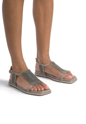 Sandali beige con tomaia testurizzata e dettagli in perle argentate. Design open-toe con cinturino alla caviglia e suola piatta.