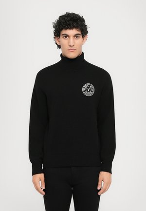 Musta neulemainen korkea kaulus, jossa on valkoinen ympyrälogo ja "Versace Jeans Couture" -teksti rinnassa. Venyvät ribbikuidut hihansuissa.