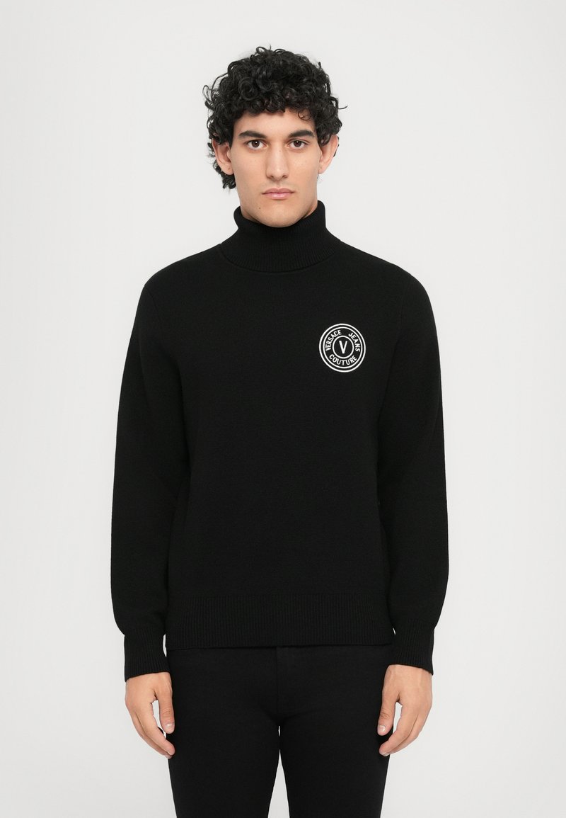 Μαύρο πλεκτό πουλόβερ με ψηλό γιακά, με κυκλικό λογότυπο σε λευκό και κείμενο "Versace Jeans Couture" στο στήθος. Ελαστικές ριμπ μανσέτες.