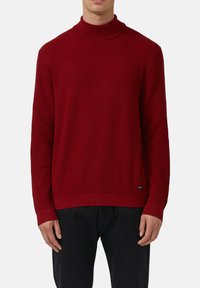 Czerwony sweter z golfem o teksturowanym splocie, z prążkowanymi mankietami i dołem. Swobodny styl, wykonany z miękkiego materiału. Brak widocznych logo.